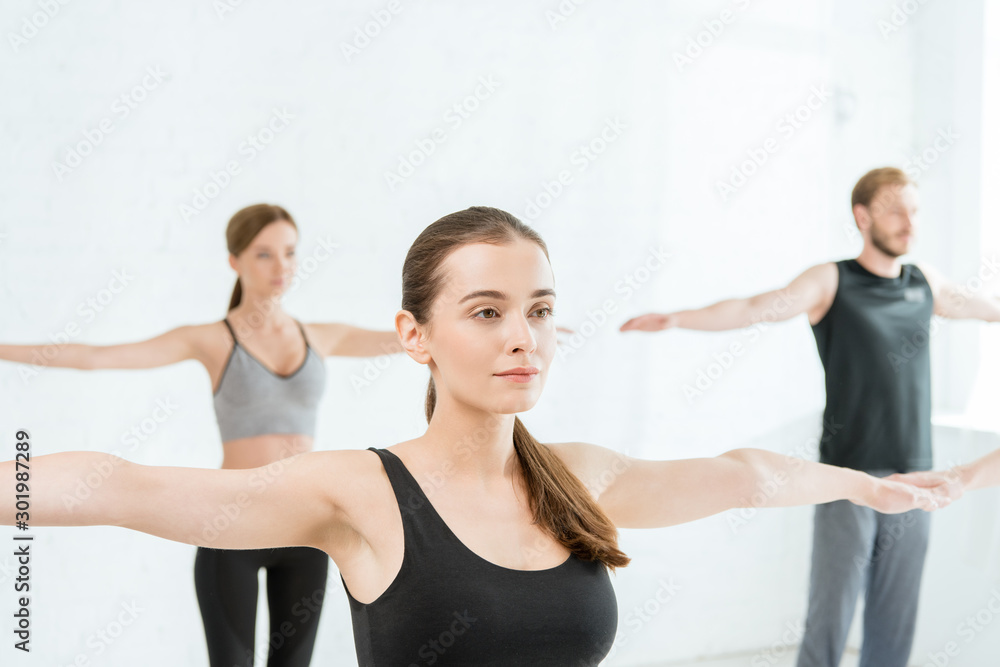 Young women and man practicing yoga in mountain open arm pose