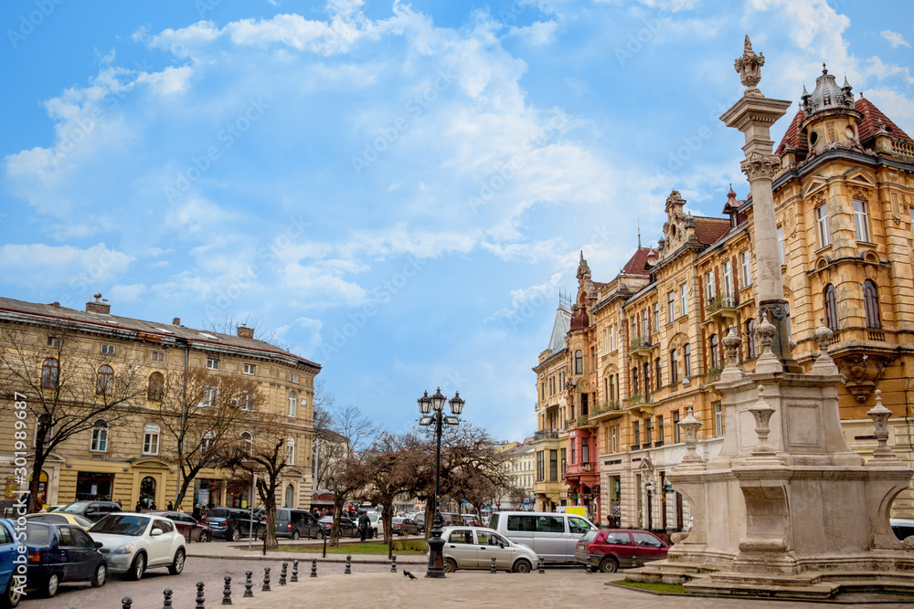 Old Street In Europe. The Square With Front Facade Of Vintage Buildings, Old Memorial  And Stone Pavement In The Historic Centre Of Lviv.