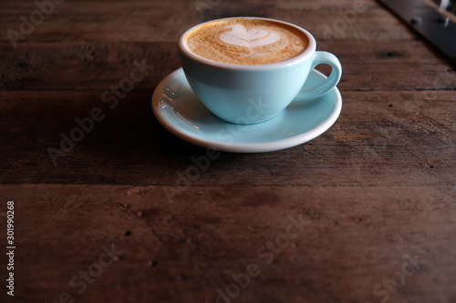 Cappuccino or latte with frothy foam  blue coffee cup top on wooden coffee shop background