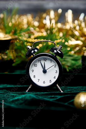 Christmas gift box, alarm clock and fir tree branch on table.