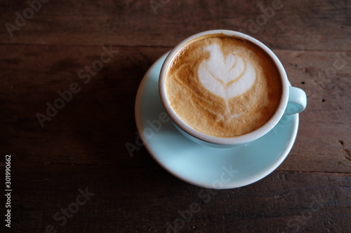 Cappuccino or latte with frothy foam, blue coffee cup top on wooden coffee shop background