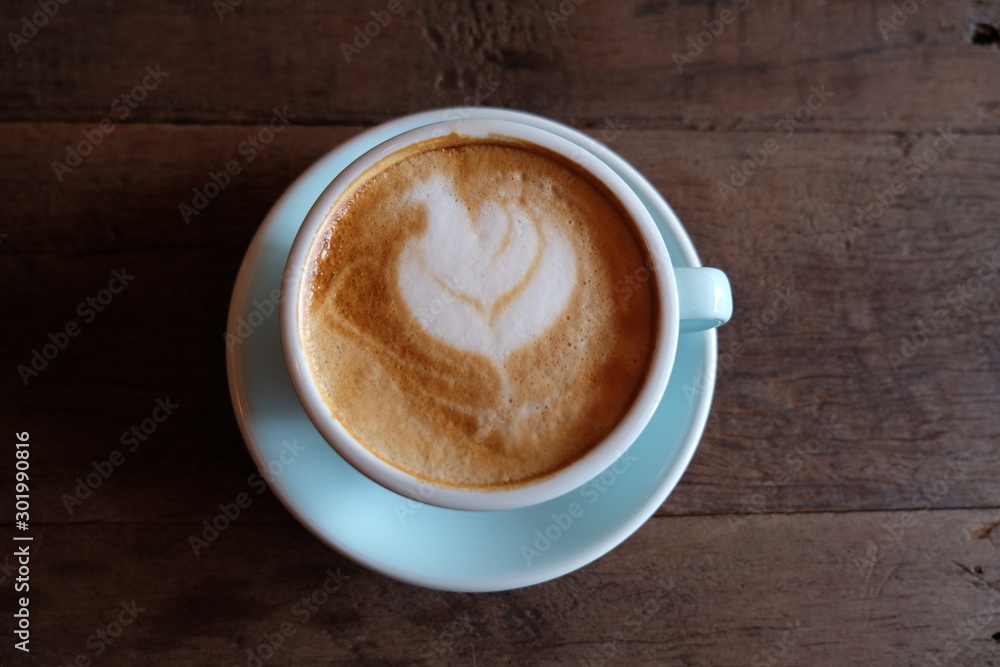 Cappuccino or latte with frothy foam, blue coffee cup top on wooden coffee shop background Cappuccino or latte with frothy foam, blue coffee cup top on wooden coffee shop background