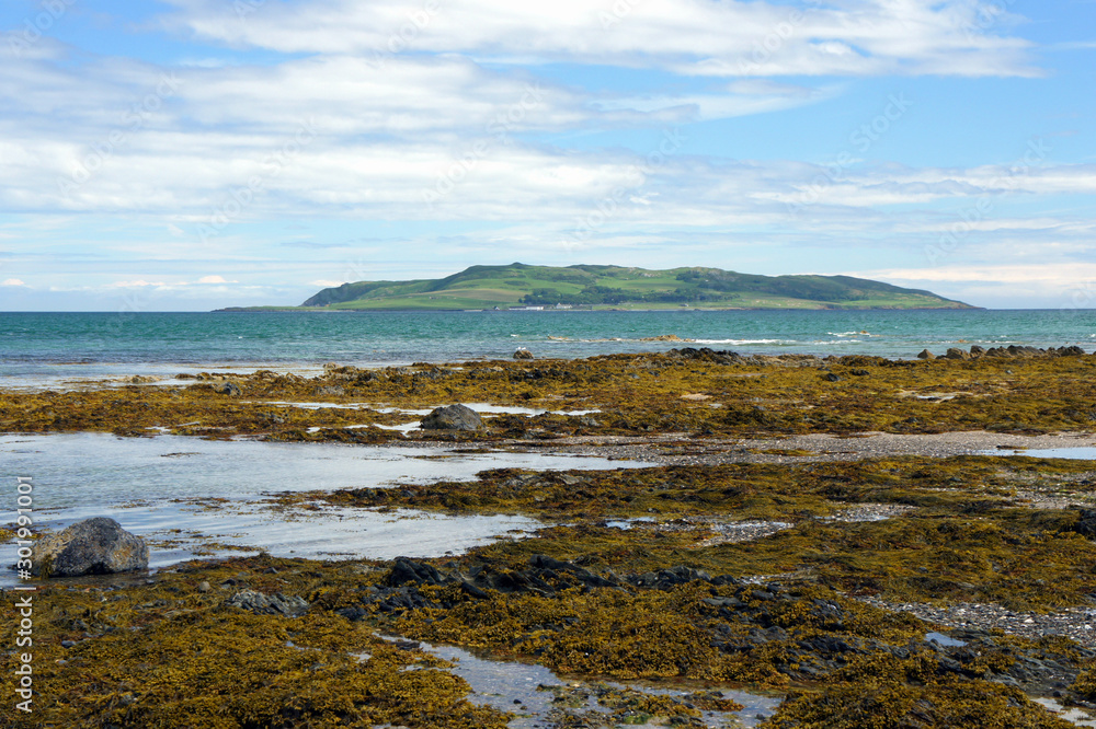 The rocky shore of the Irish Sea at low tide. On the horizon is the island of Lambay.