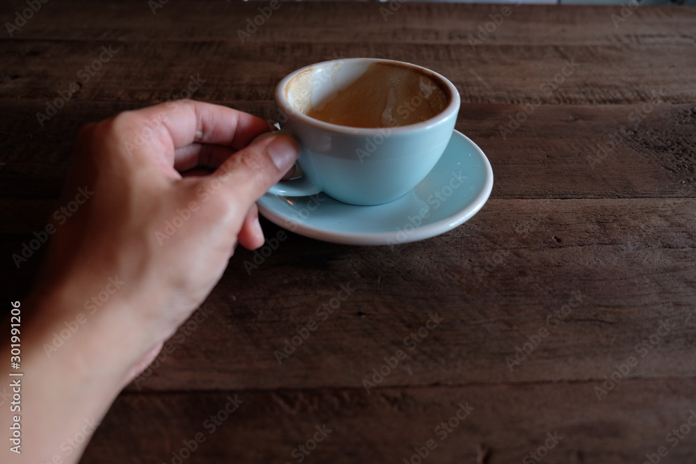 Obraz premium hands holding hot cup of coffee on rustic wooden table background