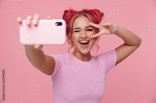 Portrait of young woman showing peace sign and taking selfie photo photo