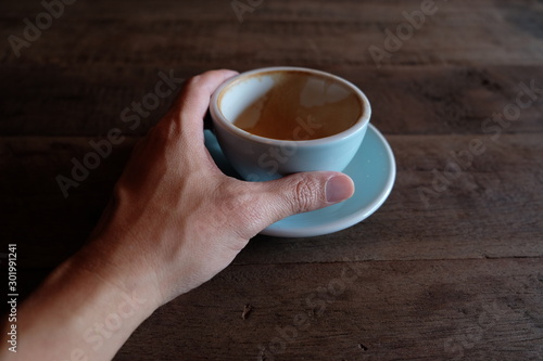 hands holding hot cup of coffee on rustic wooden table background
