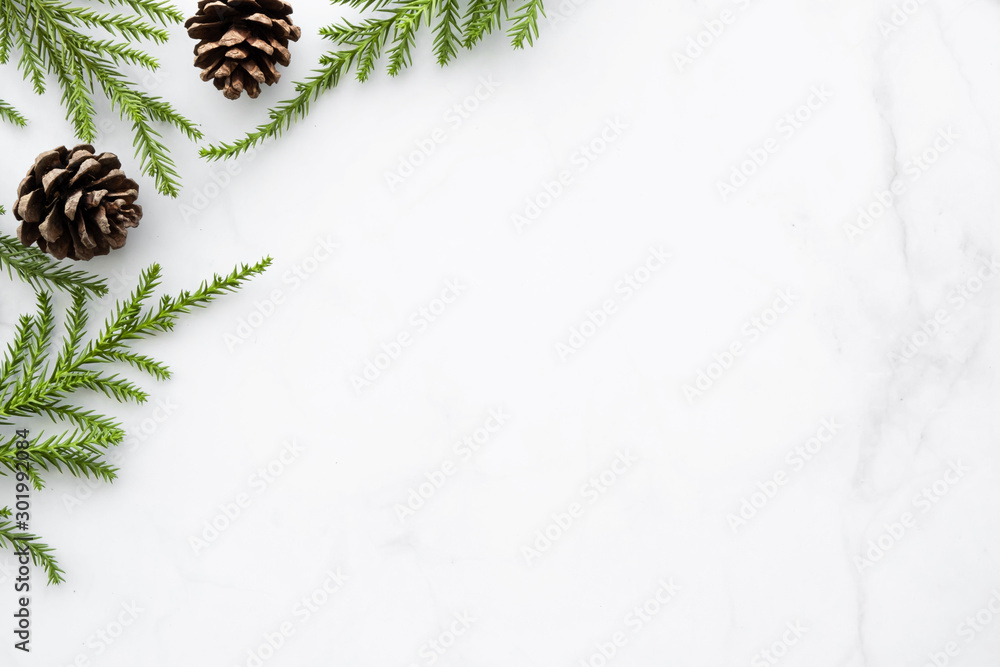 White marble table with Christmas decoration including pine branches and pine cones. Merry Christmas and happy new year concept. Top view with copy space, flat lay. - obrazy, fototapety, plakaty 