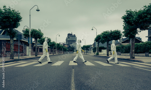 Vászonkép People with bacteriological protection suits crossing a crosswalk in a row