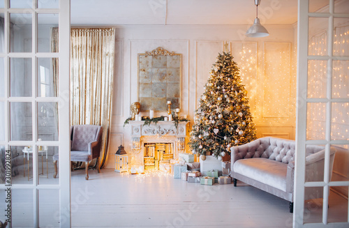 warm cozy beautiful modern design of the room in delicate light colors decorated with Christmas tree and decorative elements fireplace 