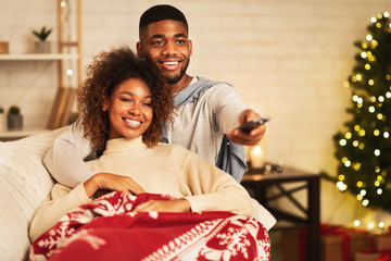 Afro couple in love at Christmas eve enjoy watching tv
