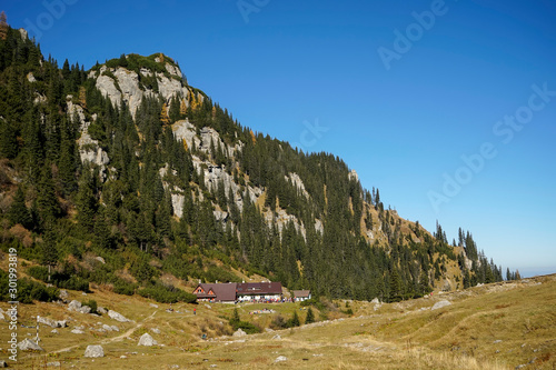 Malaesti challet in the Romanian part of the Carpathian mountains , with peaks behind and fir forest in autumn colors photo