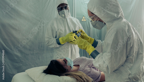 Quadro em tela Two people attending to a woman with a virus lying on a stretcher in a field hos