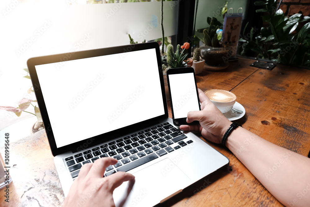 Fototapeta premium mockup image computer,cell phone blank screen for hand typing text,using laptop contact business searching information in workplace on desk at office.design creative work space on wooden desk