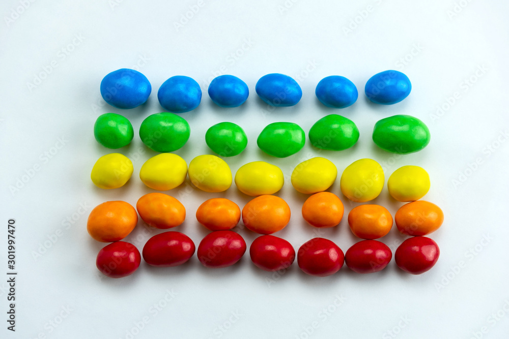 red, orange, yellow,green and blue candies rows on a white background top view flat lay, sweet rainbow red, orange, yellow,green and blue candies rows on a white background top view flat lay, sweet rainbow