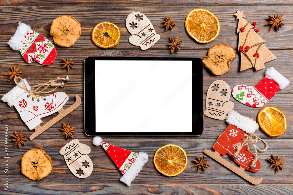 Top view of tablet on holiday wooden background. New Year decorations and toys. Christmas concept Top view of tablet on holiday wooden background. New Year decorations and toys. Christmas concept