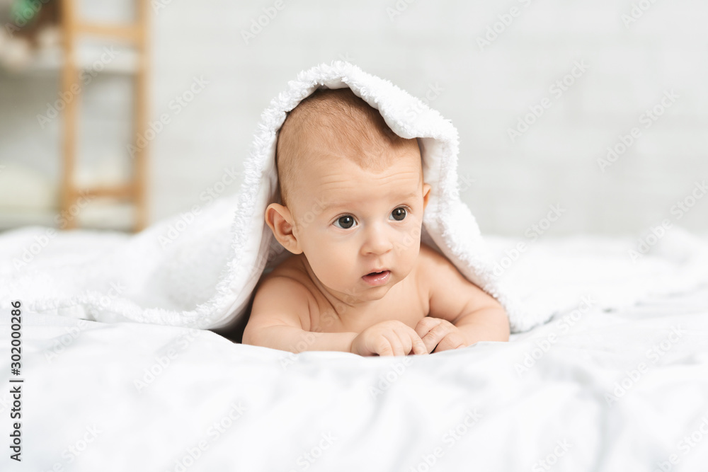 Adorable baby lying on tummy covered with soft white blanket Adorable baby lying on tummy covered with soft white blanket