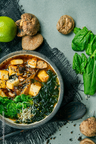 Photography Fresh vegetarian miso soup with shiitake mushrooms, tofu cheese and seaweed on a gray cloth