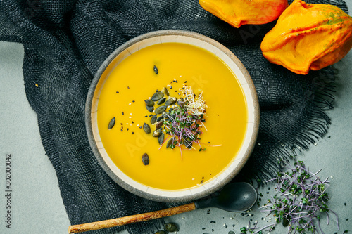 Tableau sur toile Fresh vegetarian pumpkin cream-soup with mushrooms and teriyaki sauce on a gray fabric in a composition with ginger
