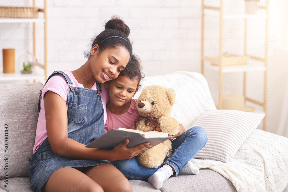 Two african sisters reading fairy tale at home Two african sisters reading fairy tale at home