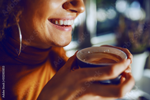 Close up of mixed race smiling woman holding coffee. photo