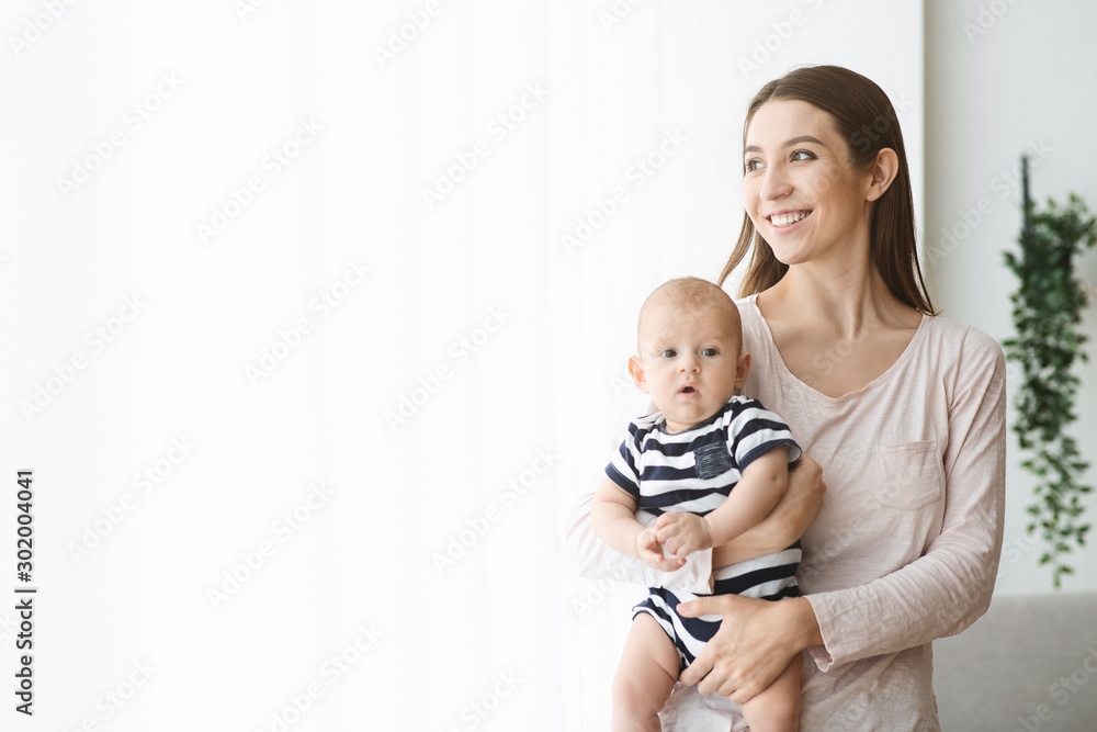 Happy mother holding newborn baby and looking out the window Happy mother holding newborn baby and looking out the window