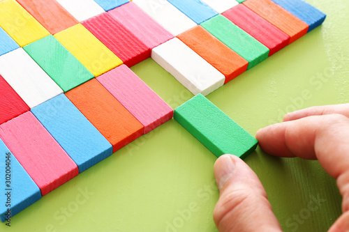 man's hand holding a domino puzzle piece, over wooden table photo