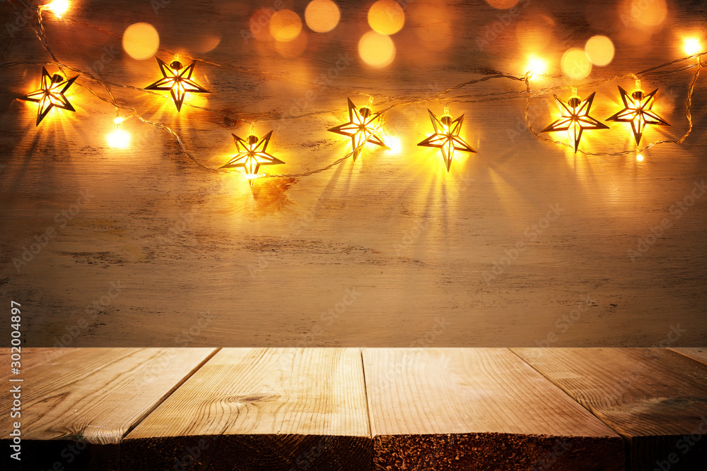 background image of wooden board table in front of Christmas warm gold garland lights. filtered. selective focus. glitter overlay - obrazy, fototapety, plakaty 