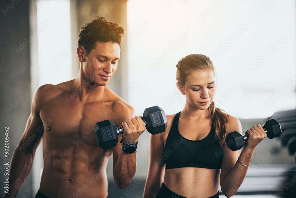 Sporty young couple with dumbbells in functional training fitness gym Sporty young couple with dumbbells in functional training fitness gym