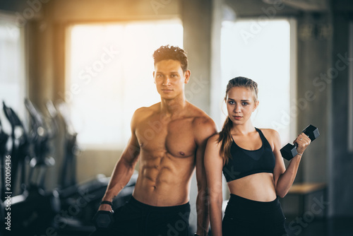 Sporty young couple with dumbbells in functional training fitness gym