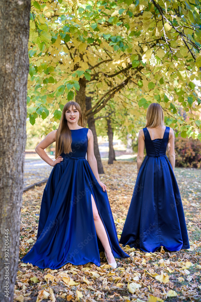 Two very beautiful young ladies in fashionable blue dresses in autumn park. Two very beautiful young ladies in fashionable blue dresses in autumn park.