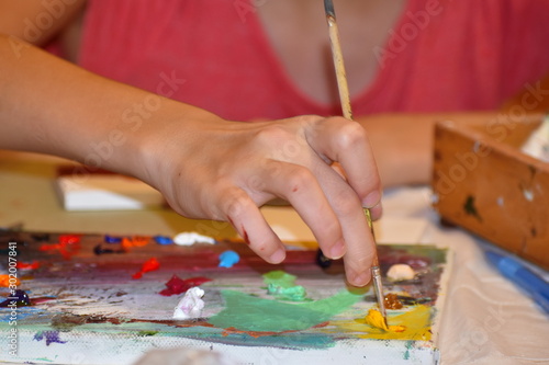 Girl draw a picture with paints. Brushes and artist's palette. Training in drawing.