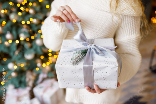 Woman's hands hold christmas or new year decorated gift box
