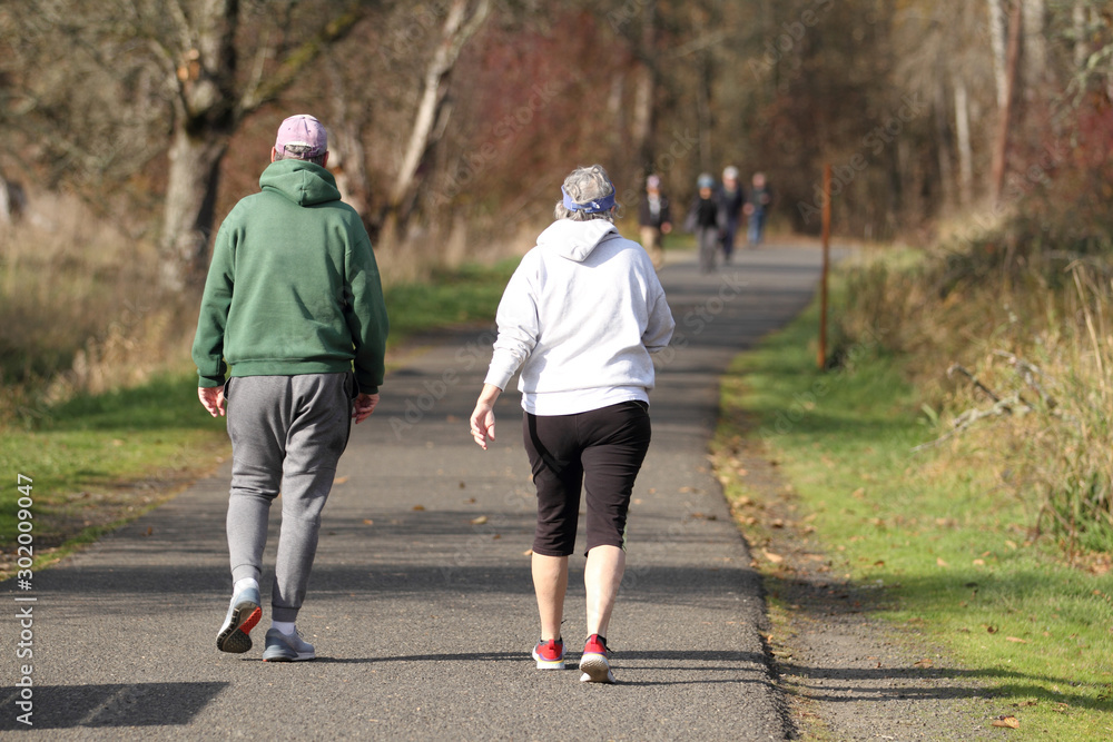 Fototapeta premium Elderly couple taking a walk in a park on a sunny day.