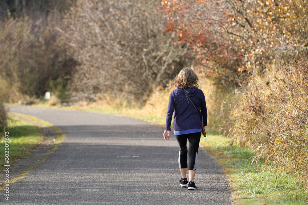 Adult woman taking a walk in a park on a sunny day. Adult woman taking a walk in a park on a sunny day.