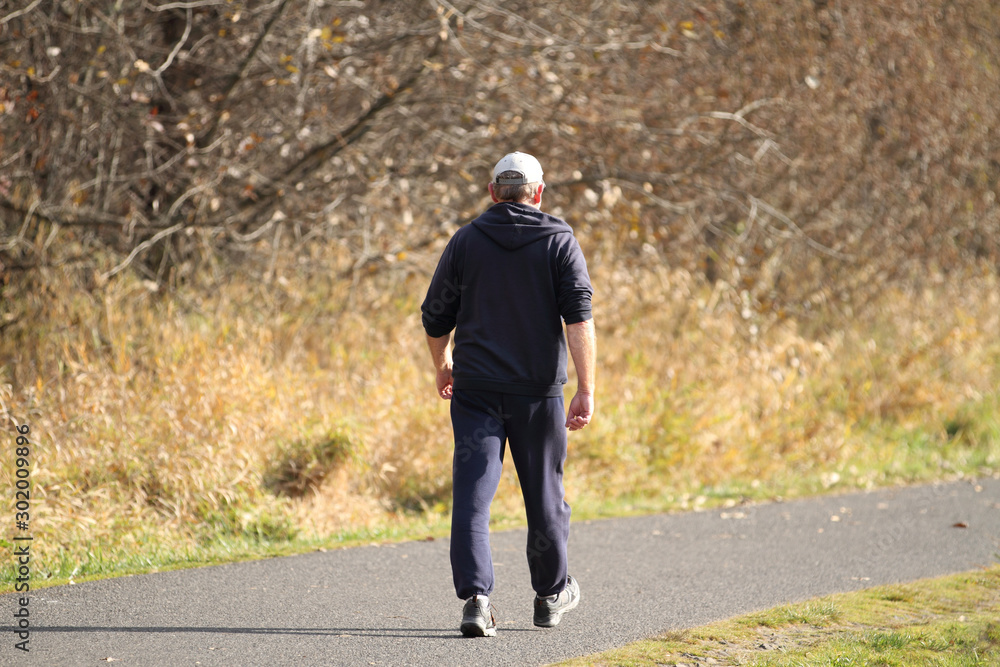 Elderly man taking a walk in a park on a sunny day.