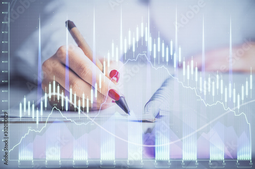 Double exposure of woman's hands making notes with forex graph hologram. Concept stock market analysis. © peshkova