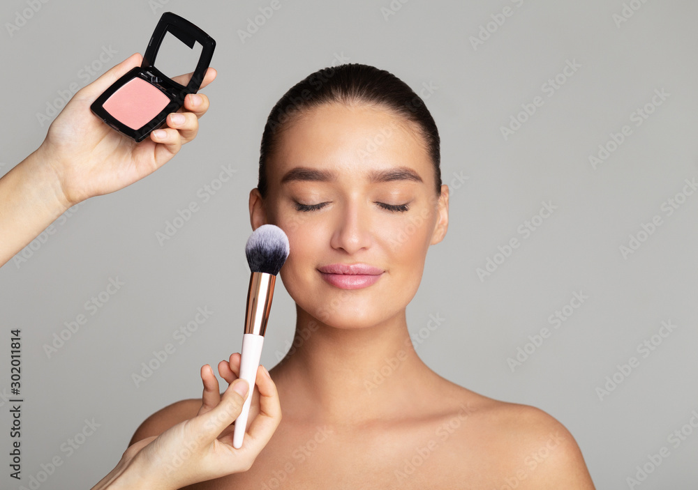 Professional makeup artist apply blush on woman cheeks Photos | Adobe Stock