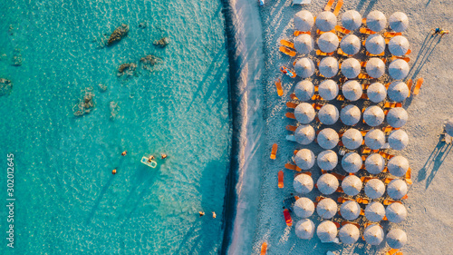 Aerial view of amazing beach with umbrellas and turquoise sea at sunset. Mediterranean sea, Crete, Greece.mazing beach with umbrellas and turquoise sea at sunset. Mediterranean sea, Crete, Greece.