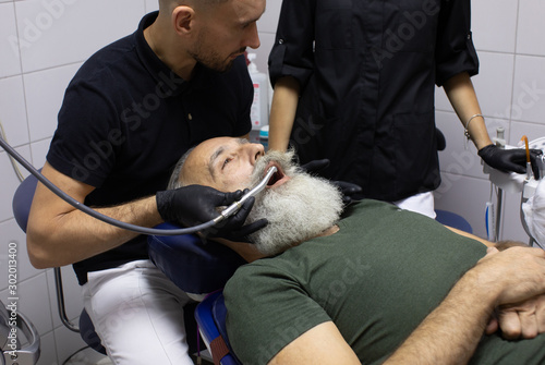 Bearded Senior man having dental treatment at dentist's office.