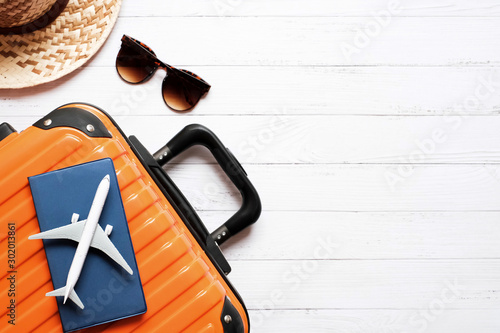 Flat lay vacation planing and traveling concept on white wooden table background with plane and passport on orange suitcase , hat and sunglasses, Top view with copy space