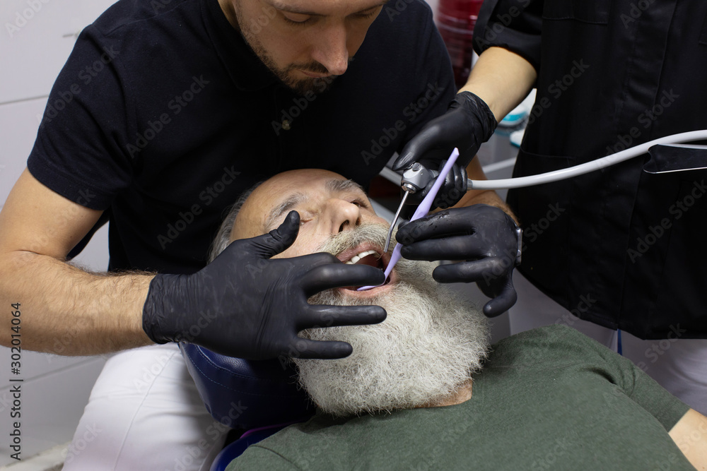 Bearded Senior man having dental treatment at dentist's office.