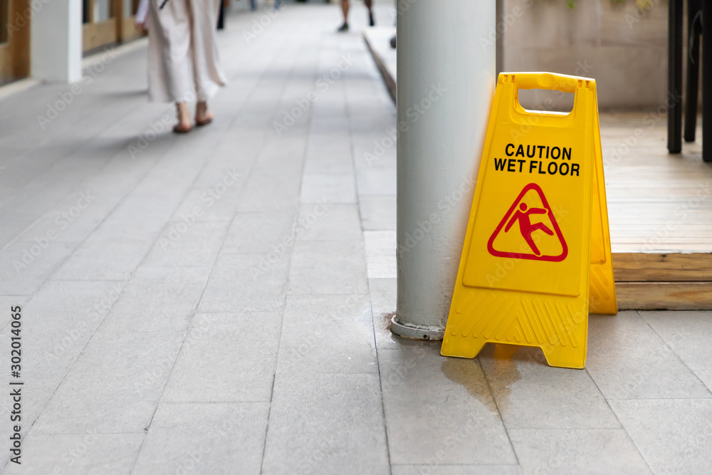 wet floor sign with water drops on wet stone floor. plastic sign