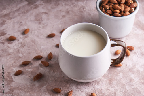 Alternative food and drink. Homemade almond milk in a cup  almond kernels on rustic background. Copy space