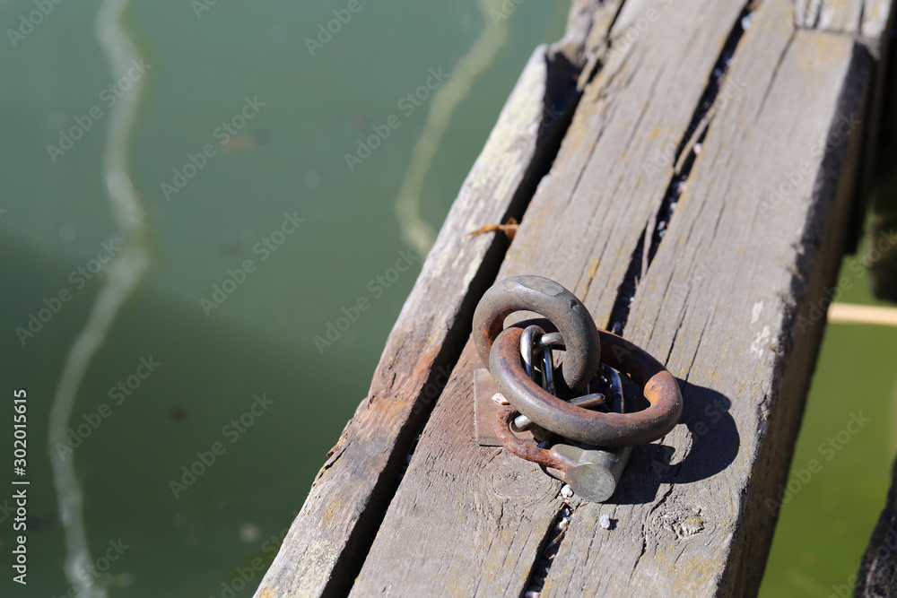 Obraz premium Metal hoop for securing a boat to the pier located in marine in Helsinki. Beautiful old and rusty chain in a closeup. Sunny summer day.