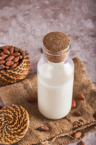 Homemade almond milk in bottle and Almond kernels on rustic background. Alternative food and drink