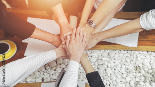Group of businessmen join hands after completing their targeted tasks.