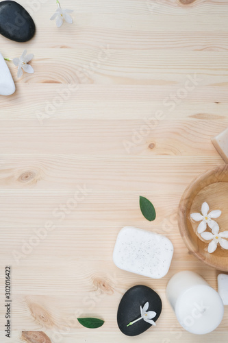 Flat lay spa products with copy space. Sea salt in bowl, towels, scrub, aroma oil in bottles and flowers on vintage wooden background. Spa composition with body care items.
