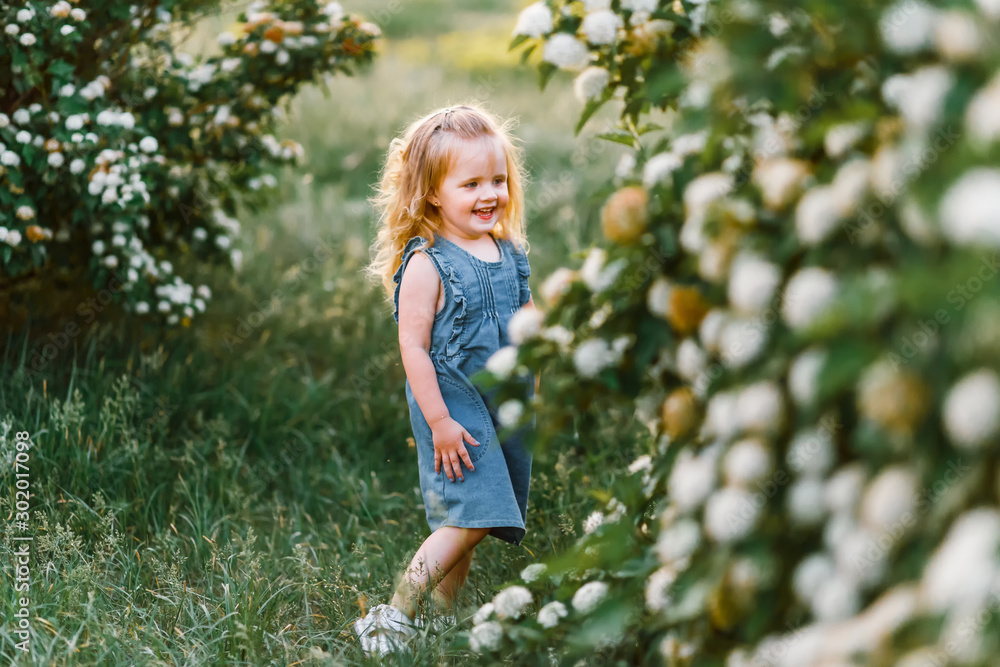 Very cute little girl with flowers in a denim sundress 