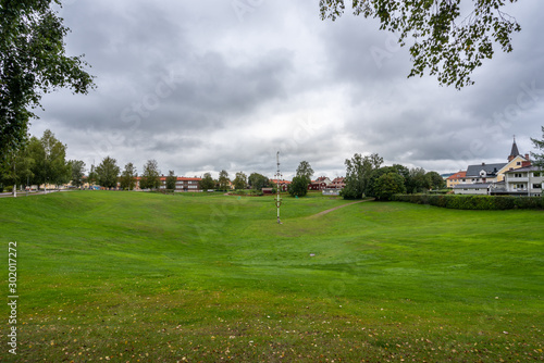 Autumn town landscape view of the large grassy pit Gropen on a green field in Leksand Sweden. © Pebo