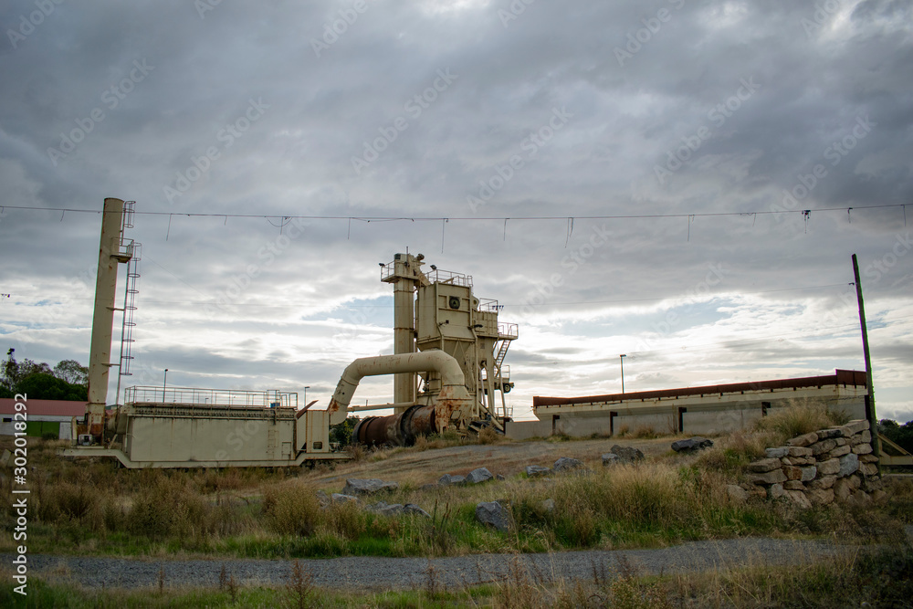 Fototapeta premium Abandoned asphalt plant in the middle of the field